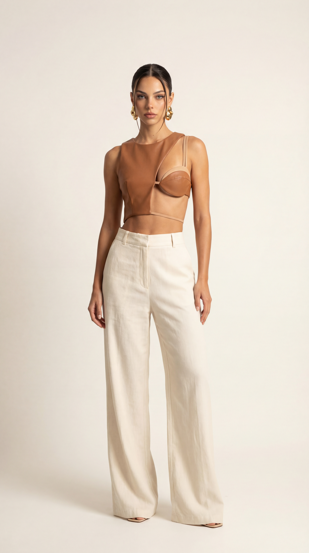 Woman wearing a brown top and wide-leg pants on a plain background