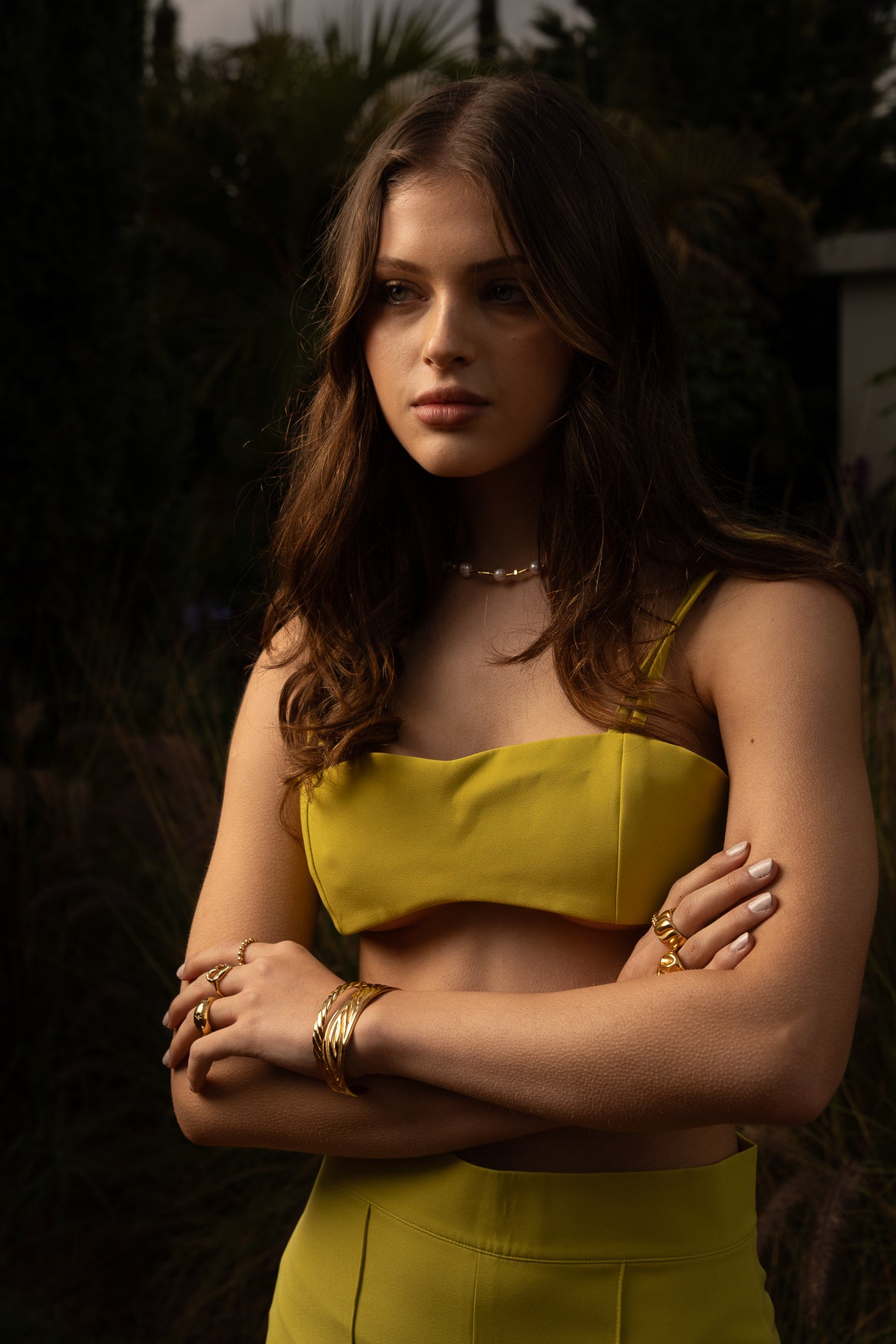 Model wearing Conventus IV Mini Top in green structured mini cropped silhouette paired with gold jewelry standing in the garden of a luxury italian villa.